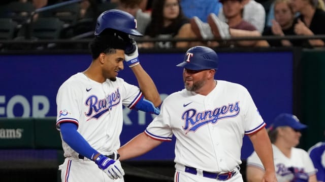 Texas Rangers left fielder Bubba Thompson, left, is congratulated by first base coach Corey Ragsdale after bunting for his first MLB hit during a game in August 2022 against the Chicago White Sox at Globe Life Field.
